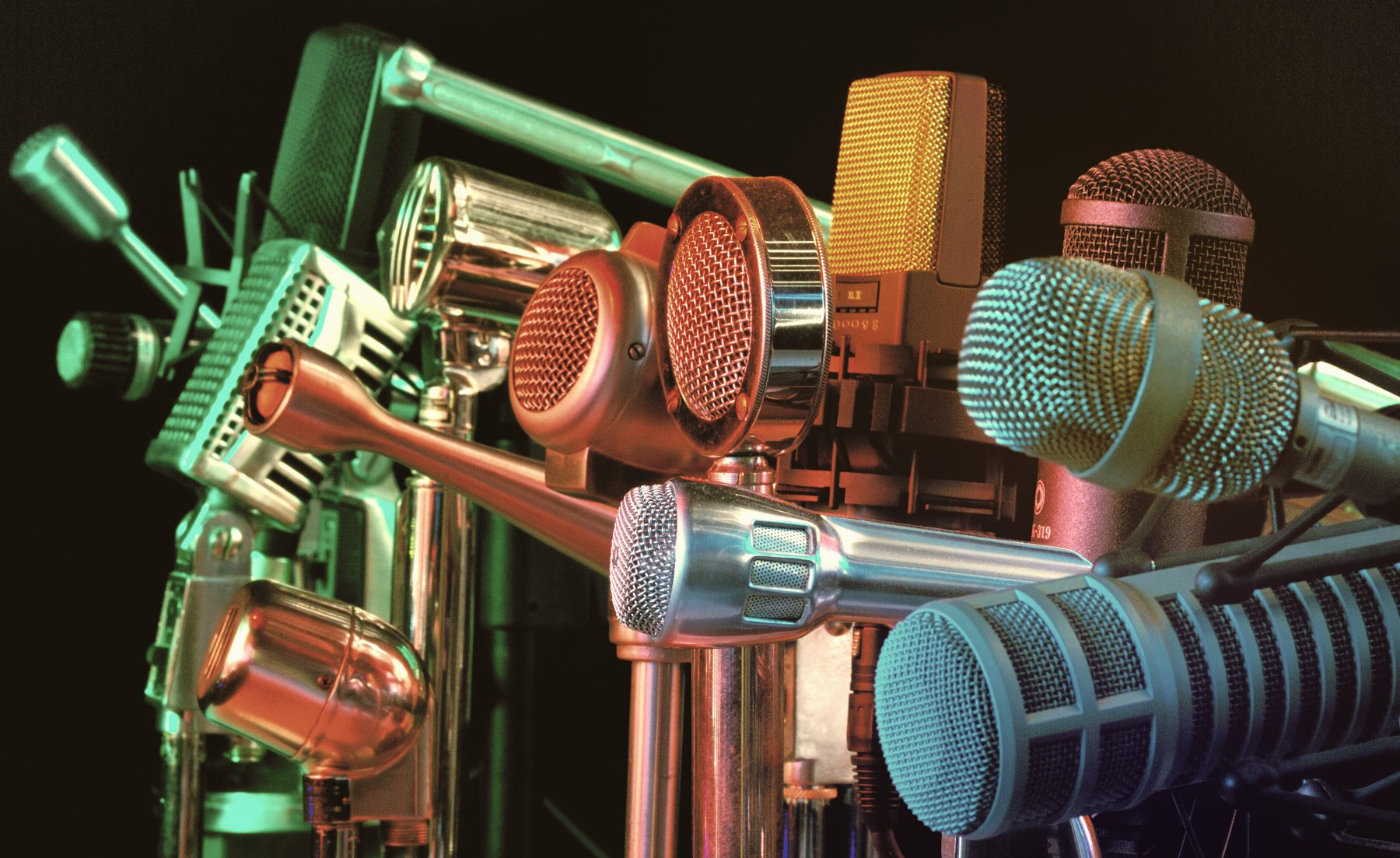 A collection of classic and modern studio microphones under colored light